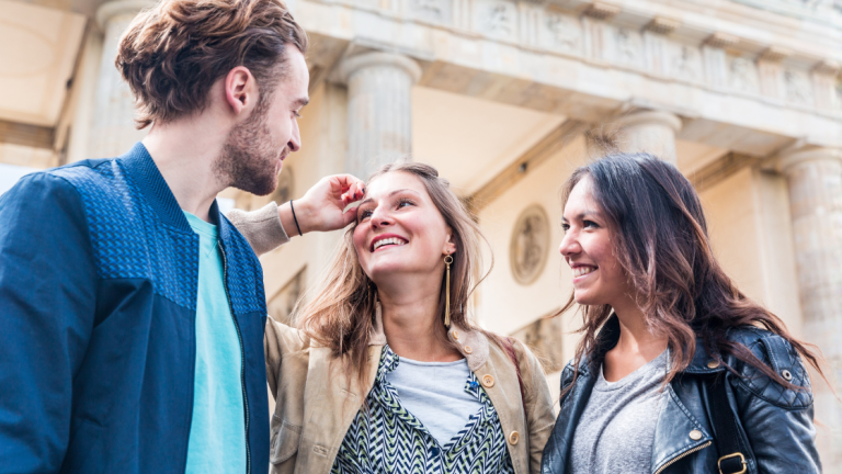 Three friends laughing together in Berlin in front of the Brandenburg Gate