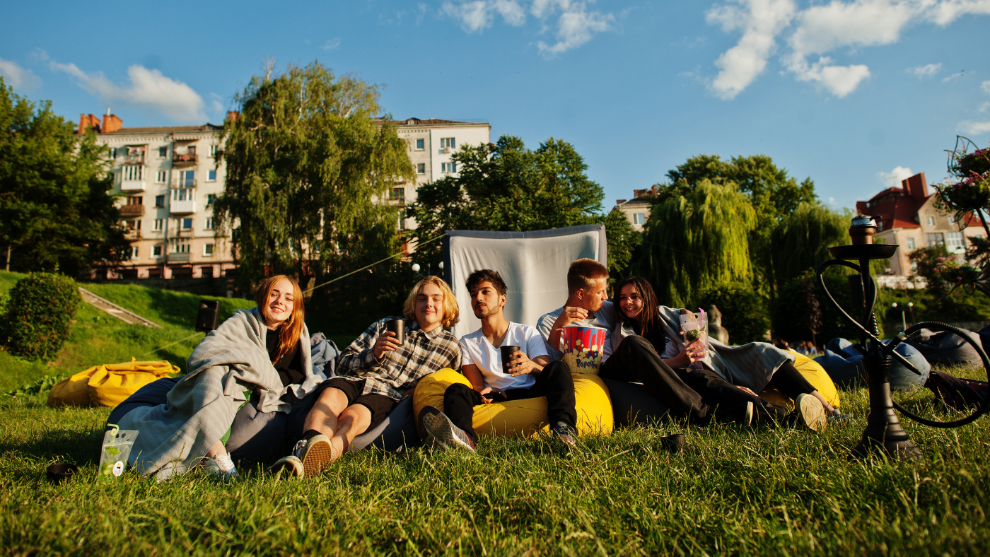A group of relaxed friends sitting together outdoors on a sunny day in Berlin, representing a real social circle built over time