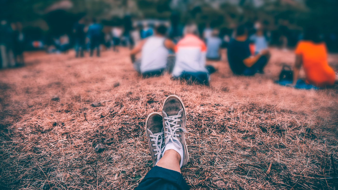 First-person view of someone sitting apart from a crowd of people, capturing the feeling of loneliness and being an outsider in Berlin