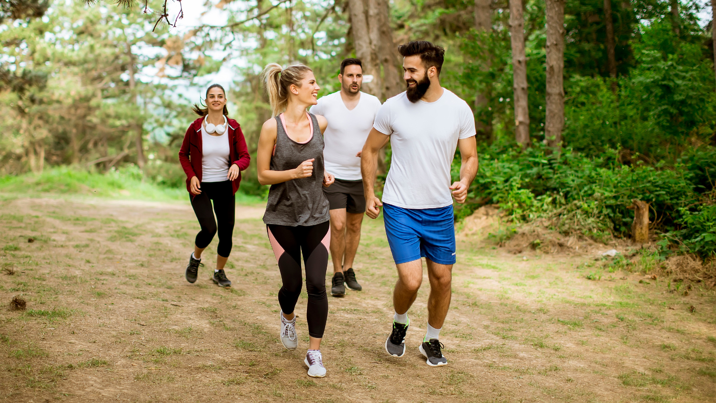 A small group of friends running together on a forest trail in Berlin, illustrating how shared recurring activities build friendship