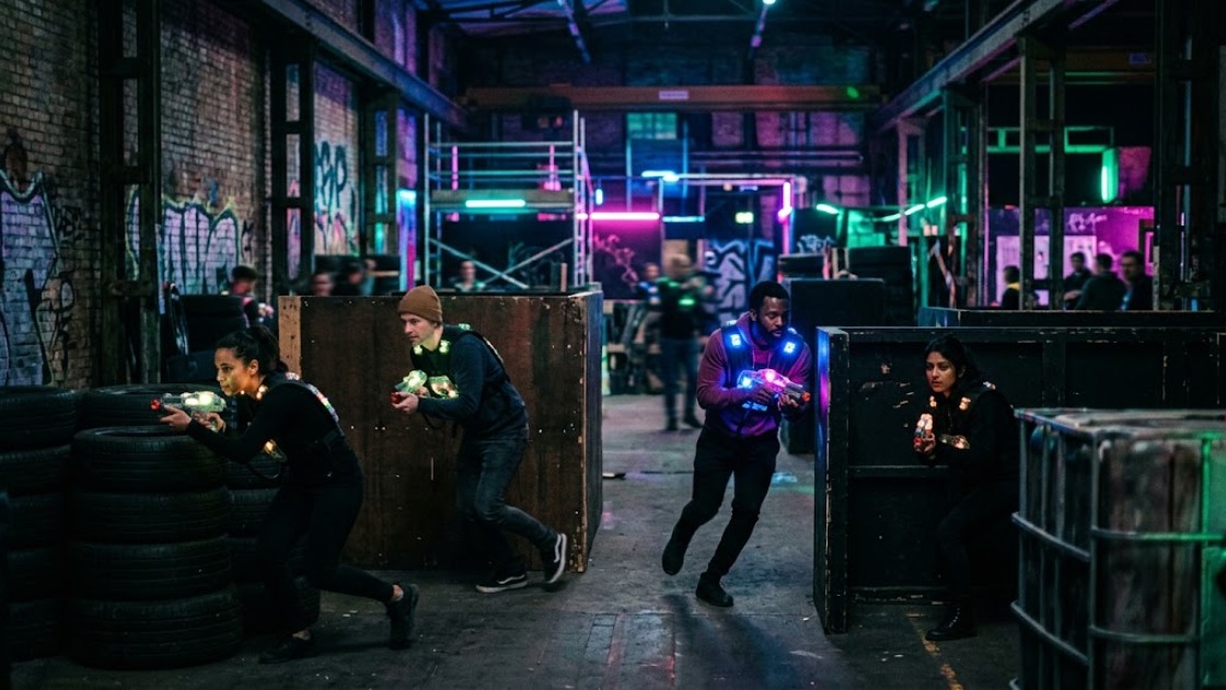 Laser tag in Berlin: four players in glowing vests mid-game in a neon-lit indoor arena