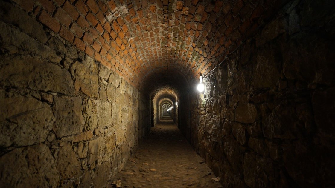 Dimly lit stone tunnel with a single lamp, the kind of setting used for Halloween haunts