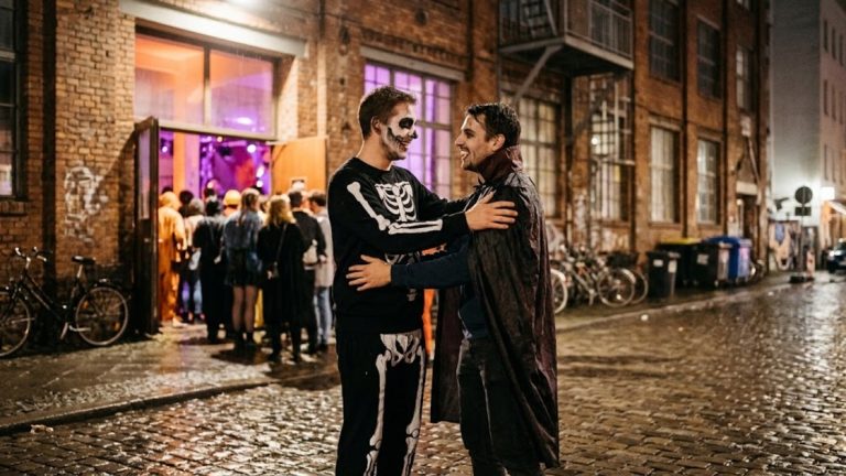 Halloween party Berlin: two friends in skeleton and vampire costumes greet each other outside a club on 31 October