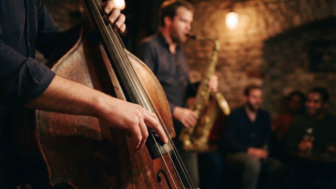 Close-up of a bass player plucking a double bass during a jam session, a saxophonist blurred behind