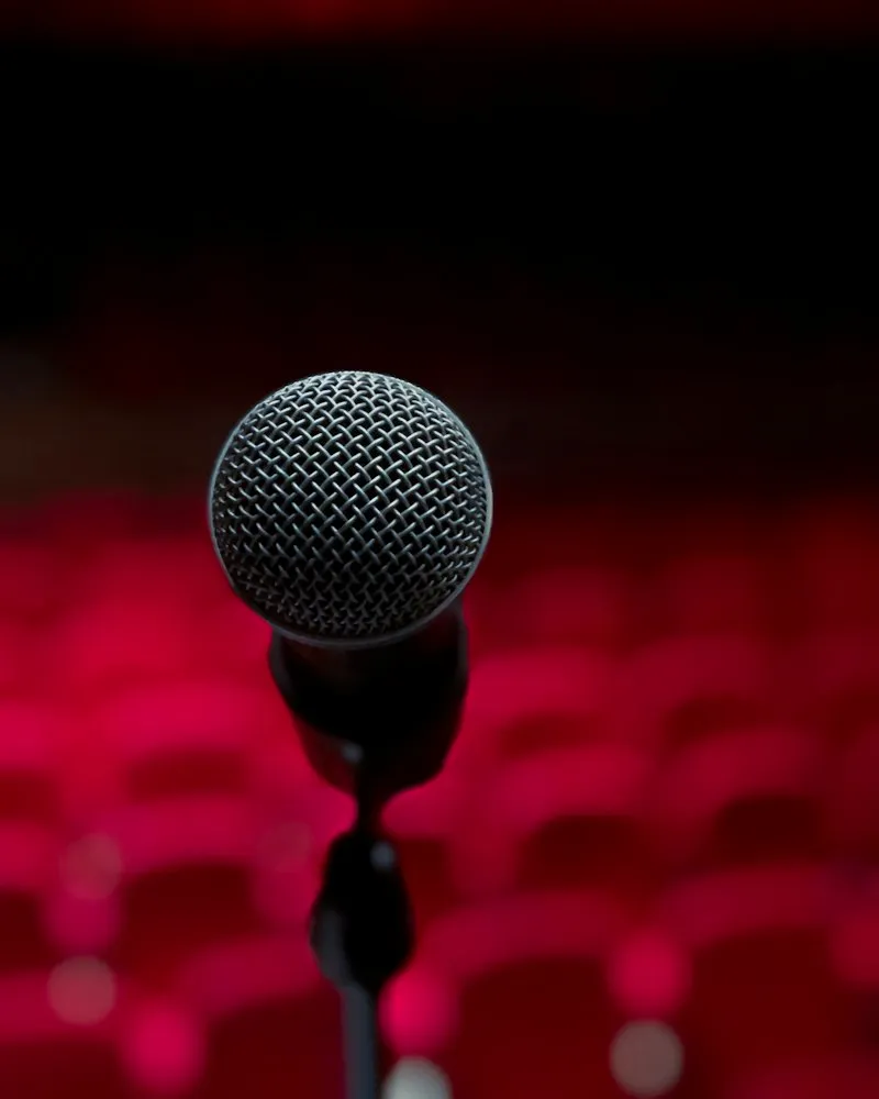 A microphone on stage in front of red theatre seats
